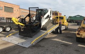 Bock's Service yellow flat-bed hauling truck with the bed tipped down