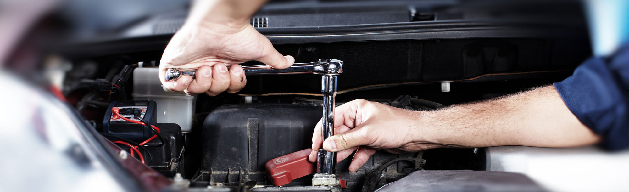 Mechanic tightening bolts under the hood of a car