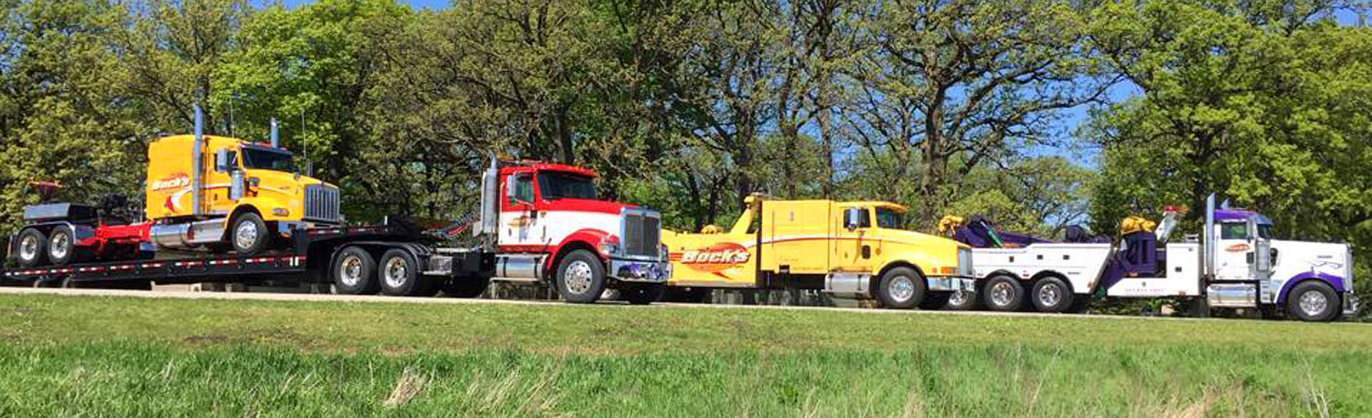 Row of Bock's Service tow trucks along the side of the road